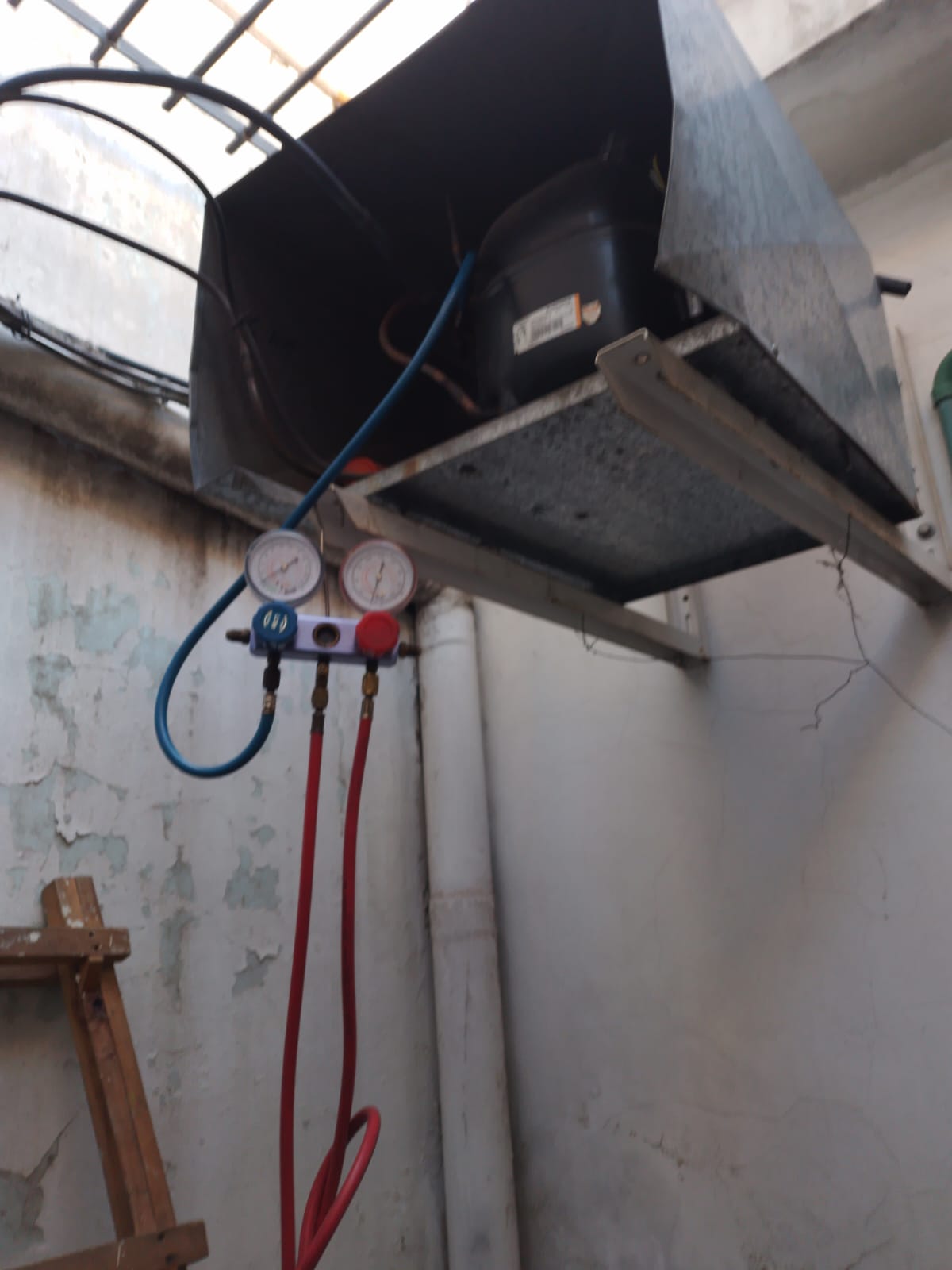 Técnico midiendo presiones con manifold en una unidad condensadora